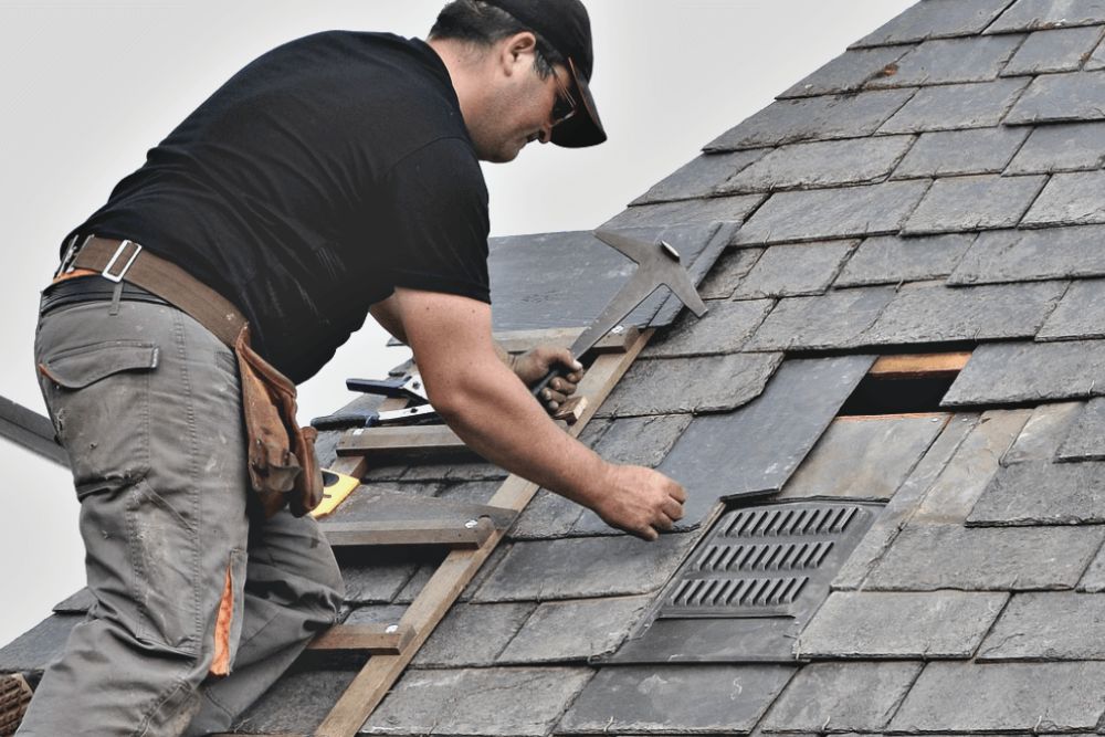 A man repairs a roof using a ladder, showcasing roof repair services in Tacoma, WA.