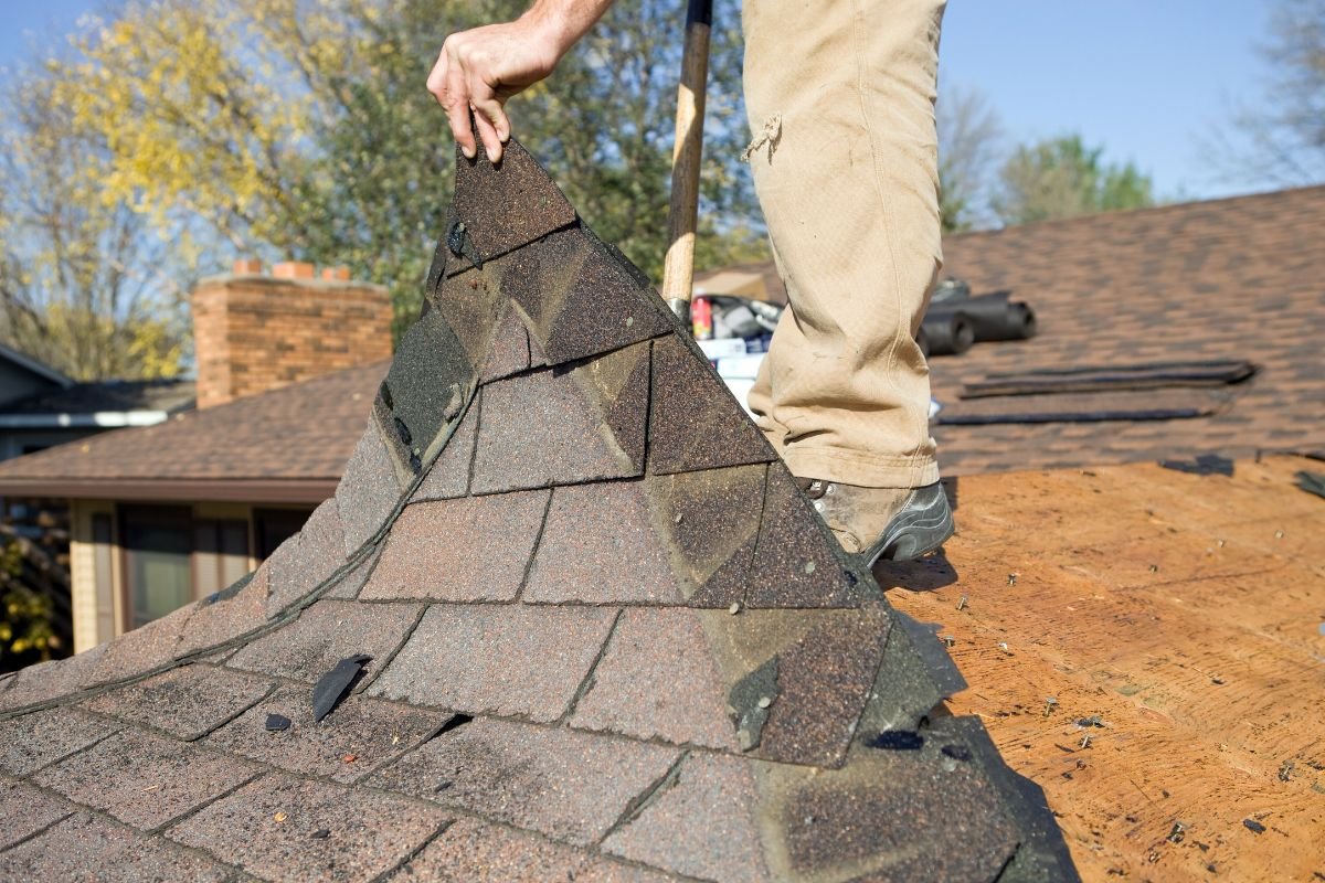 A man working diligently to install a roof on a house as part of a roof replacement.