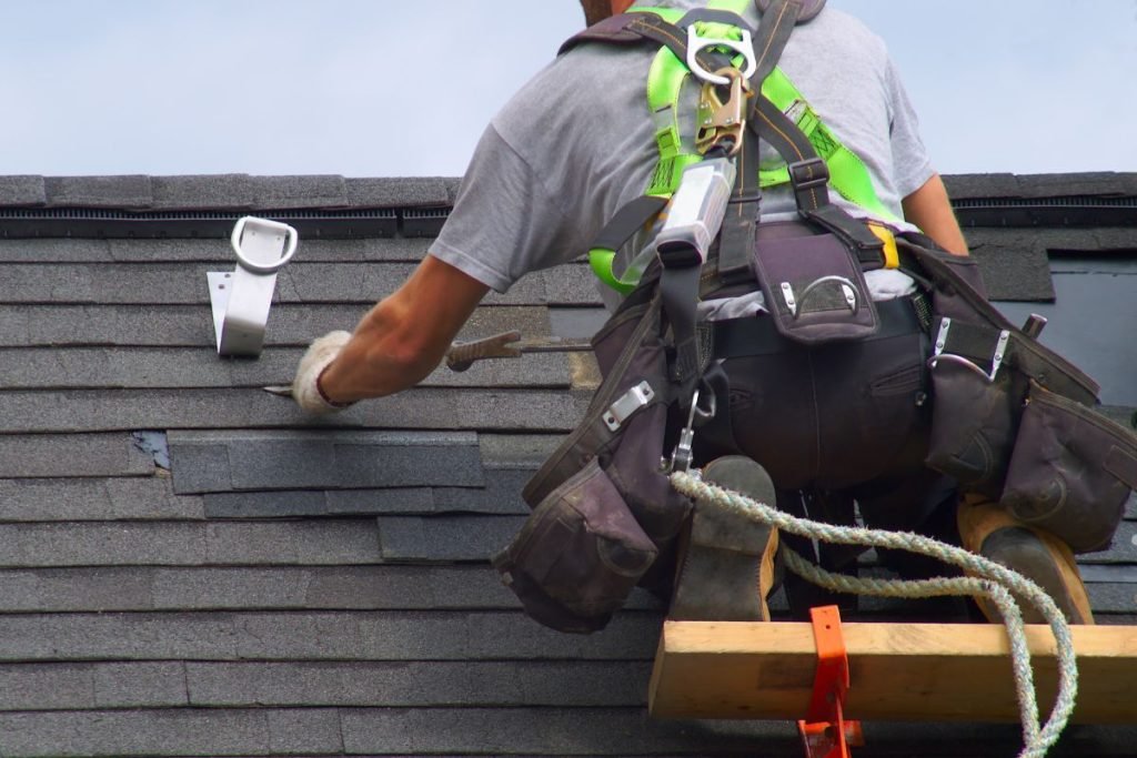 A man is engaged in roof replacement, utilizing a ladder for access to the roof.